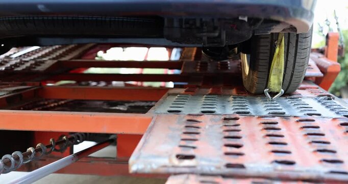 A detailed look at a car being loaded onto a trailer during a bright day. The process showcases the precision of the ramps and the careful maneuvering of the vehicle.