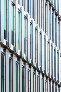 White modern facade with vertical windows and repeating structural lines creates a clean pattern in architecture across a tall contemporary building surface