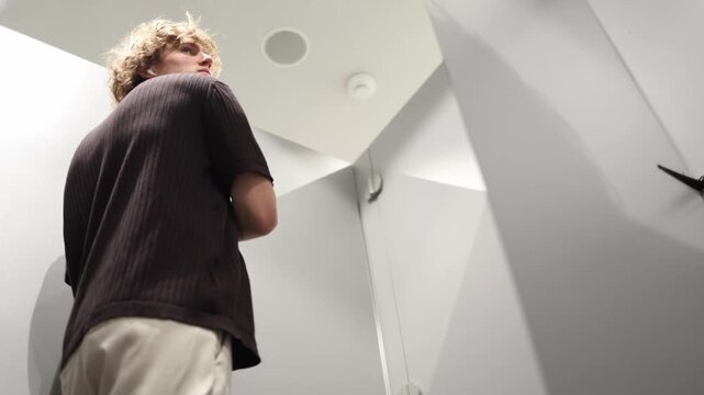 Man checks how his T shirt fits from the back while shopping for clothes carefully studying the silhouette comfort and overall appearance before deciding whether to buy it