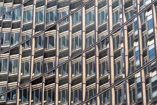 Office building facade with repeating windows and structural grid patterns where architecture fills the frame with dense geometric rhythm and urban texture