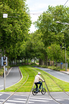 Cyclist following a green bicycle route through an urban crossing in Lyon France with trees grass and everyday mobility integrated into the city