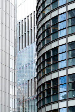 Modern glass facade with curved windows and vertical architecture on a building where repeated windows and glass create an abstract facade pattern across the frame
