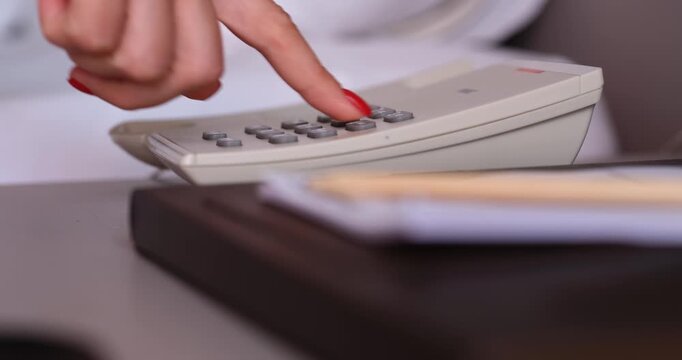 A person is focused on dialing a phone number, showing determination as they navigate a busy workspace filled with documents and notes. The atmosphere is filled with purpose and urgency.