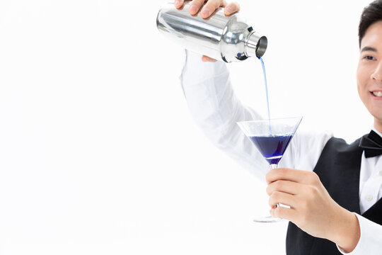 Bartender pouring blue cocktail from shaker