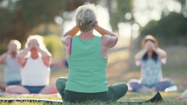 Senior woman practicing yoga meditation outdoors in a park