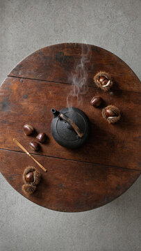 teaming Cast Iron Teapot and Chestnuts on Round Rustic Wood Table