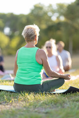 Fototapeta premium Senior woman meditating in outdoor yoga class
