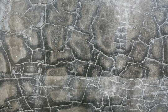 Detailed view of dark mottled concrete surface background with crack lines