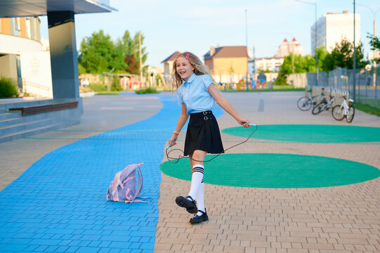 A happy schoolgirl skipping rope outside school