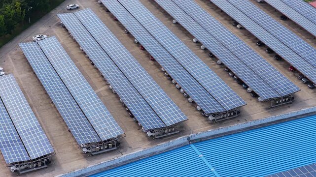 Forward aerial reveal of solar carports beyond a solar panel roof