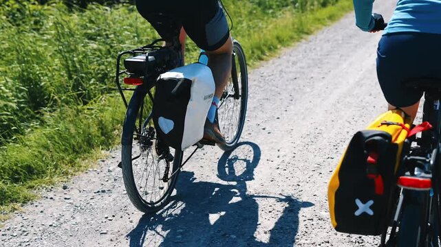 Close-up of a cyclist pedaling legs and rear panniers on a touring bike riding along the EuroVelo 10 gravel route in the Danish countryside on a sunny summer day