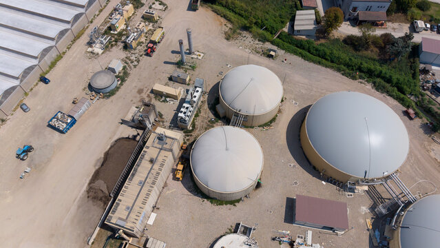 Aerial view of a biomethane plant with large dome-shaped biogas digesters and industrial infrastructure in San Giuliano Milanese, Lombardy, Italy.