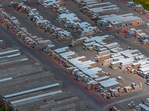 Aerial view of a large industrial storage yard filled with neatly stacked construction materials and concrete blocks arranged in rows in Otnice, South Moravian Region, Czechia.