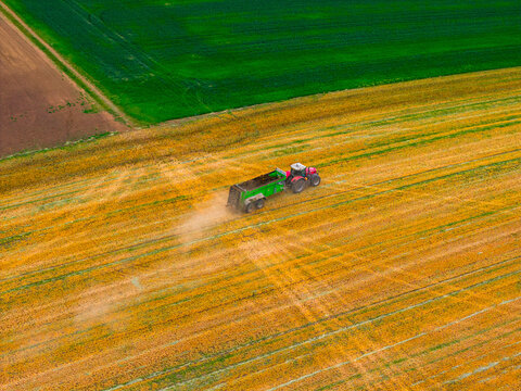 Aerial view of a tractor pulling a trailer through a field in Cejkovice, South Moravian Region, Czechia.