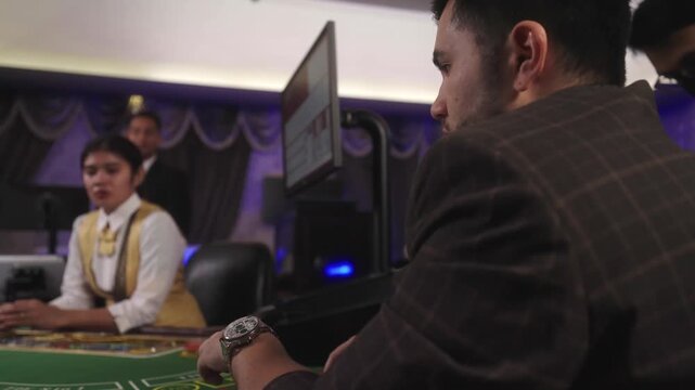 Commercial casino table gaming with scene of a male player spinning and tossing casino chips while waiting for his turn to play.