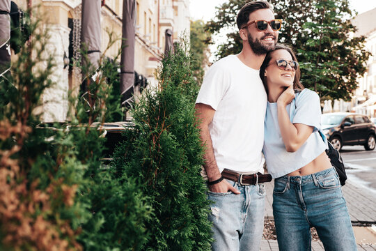 Smiling beautiful woman and her handsome boyfriend. Woman in casual summer jeans clothes. Happy cheerful family. Female having fun. Sexy couple posing in the street at sunny day. In sunglasses