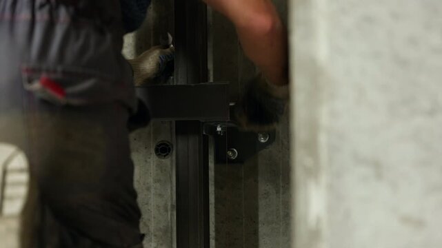 Worker fastening elevator guide rail connection inside lift shaft