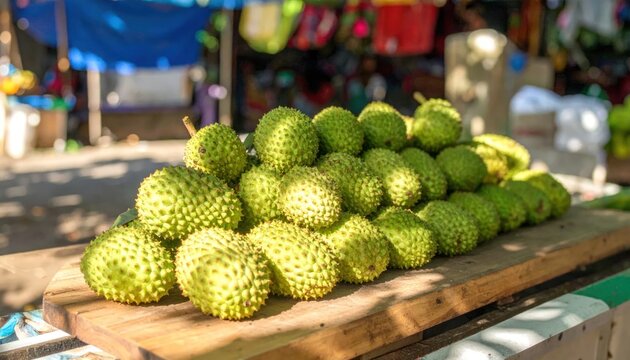 Fresh green custard apples stacked on wooden market board.