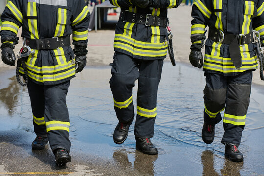 Firefighters in Protective Turnout Gear Walking Through Water During Training Exercise Demonstrating Teamwork