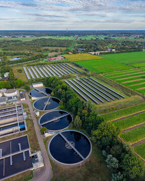 Aerial view of the RWZI Horstermeer wastewater treatment plant with circular sedimentation tanks and a solar panel field in Nederhorst Den Berg, Noord-Holland, Netherlands.