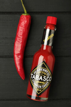 Mykolaiv, Ukraine - August 19, 2026: A bottle of Tabasco pepper sauce with red chili pepper on black wooden background