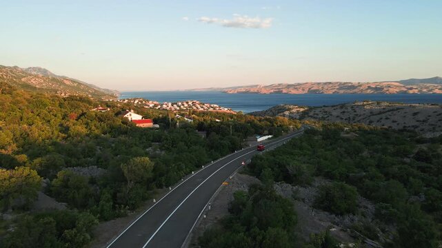 Car driving along a winding road through green hills near the sea