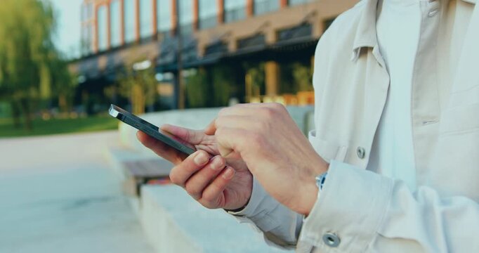 Close up of males hands use mobile phone outdoors