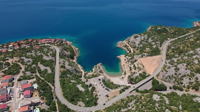 Winding coastal road around rocky bay with turquoise sea