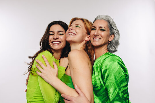 Three women hugging and laughing in studio