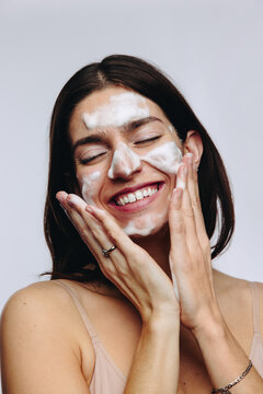 Woman washing face with foam and smiling