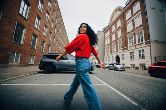 Walking through the city, the woman heads for an electric car charger while using her phone