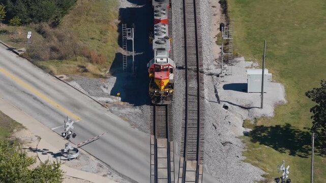 Freight locomotive crossing a road at a railroad crossing in Gentry, Arkansas, aerial pullback as steam rises from train
