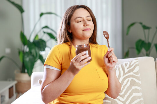 Woman enjoying chocolate spread on sofa