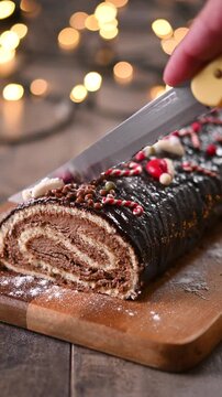 Slicing a traditional Christmas yule log cake with christmas decoration background