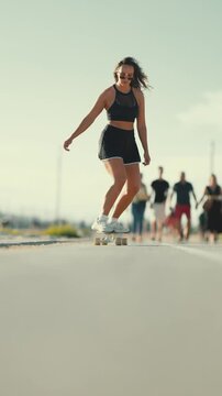 Young woman longboarding towards camera outdoors
