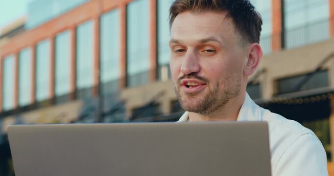 Close up. Portrait of smiling confident Caucasian man using laptop computer communication, having video call sitting outdoors.