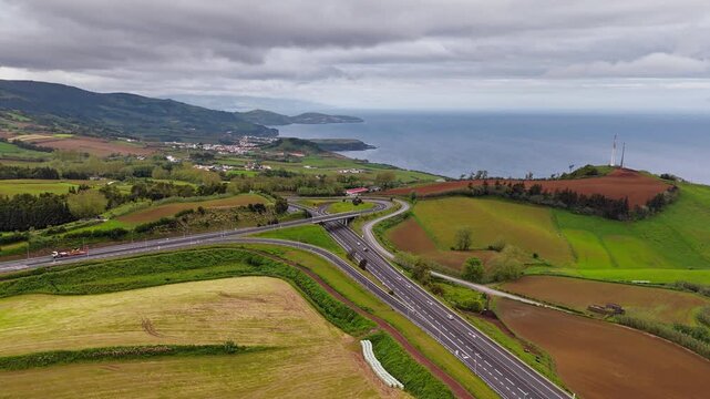 Aerial top view of multi level highway interchange surrounded by agricultural land on Sao Miguel, Azores