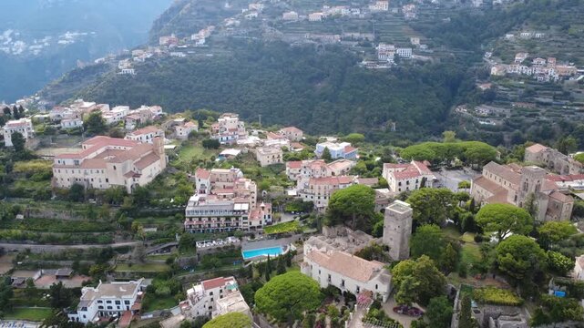 Aerial forward flight over Villa Rufolo and Ravello hilltop town towards green valley 4K