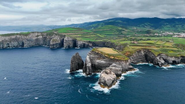Sao Miguel rocky headland rises above the Atlantic Ocean in Azores, Portugal. Steep volcanic cliffs give this island coastline distinctive coastal profile