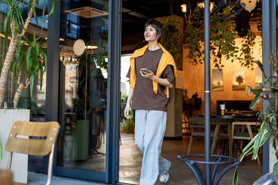 Smiling short-haired woman near the cafe entrance looking positive
