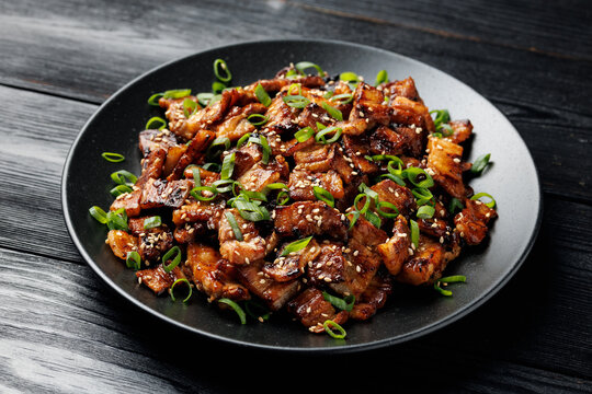 Korean Pork Belly with Sesame Seeds and Green Onions on Black Plate