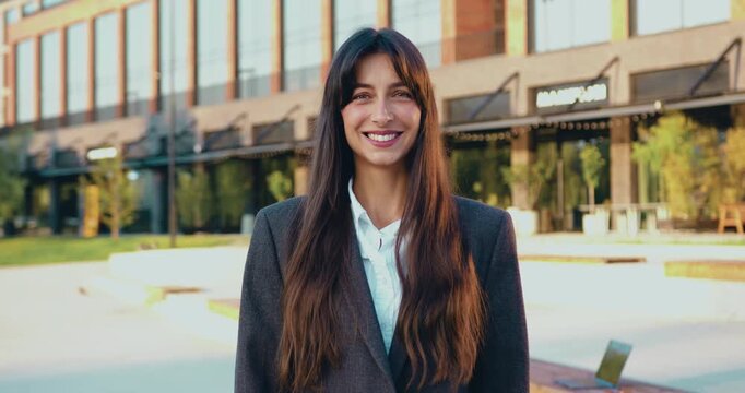 Adult 30-35s Caucasian woman looking at camera, smiling toothy standing outside outdoor near company, slow motion