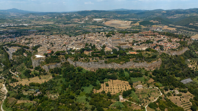 Aerial panorama of Orvieto, a hilltop town in the province of Terni, Umbria, Italy. The historic center sits atop a plateau of volcanic tuff. It's surrounded by countryside and olive groves.