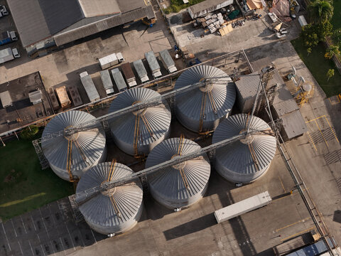 Aerial view of industrial grain silos arranged in a cluster at a storage facility with trucks parked nearby in Santo Domingo, Distrito Nacional, Dominican Republic.