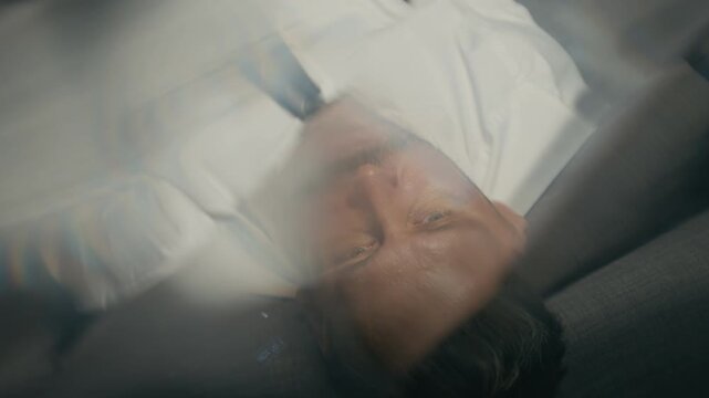 Caucasian middle aged businessman lying unconscious on sofa after alcohol abuse from top view. Video suited for mental health projects, corporate burnout, and addiction awareness