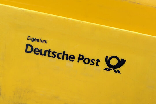Heidelberg, Germany - March 2nd 2026: Deutsche Post (German postal service) logo and text centered on yellow background letter box