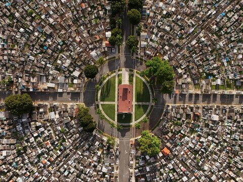 Aerial view of the Maximo Gomez National Cemetery featuring its circular layout, central building, dense rows of graves, and green trees, Santo Domingo, Distrito Nacional, Dominican Republic.