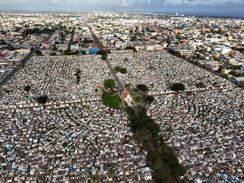 Aerial view of Maximo Gomez National Cemetery featuring a dense grid of white tombs and a central chapel surrounded by the urban sprawl of Santo Domingo, Distrito Nacional, Dominican Republic.