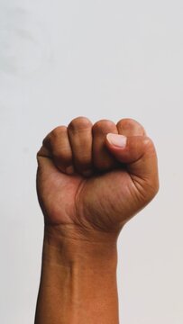 A raised fist representing strength resistance and unity against a plain white background.