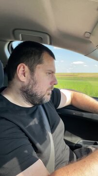sleepy male driver begins to nod off with one hand on the steering wheel during a daytime rural journey, demonstrating microsleep, impaired attention and serious collision risk